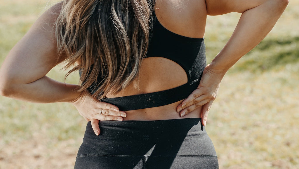 A woman in yoga pants holding her back